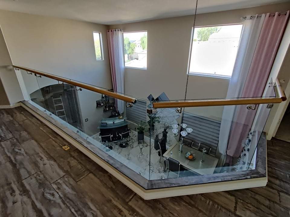 Wrap-around glass balcony railing with wood handrail